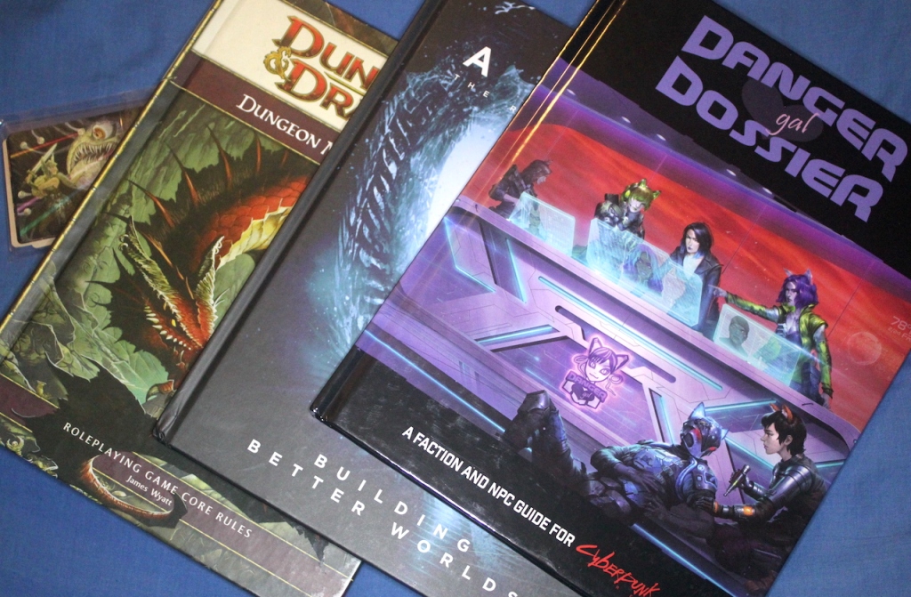 Three books, Danger Gal Dossier for Cyberpunk Red, Bulding Better Worlds for the Alien RPG, the 4th edition Dungeons and Dragons Dungeon Master's Guide.